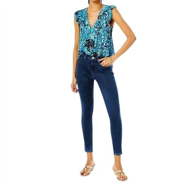 Woman wearing a blue floral top and Lilly Pulitzer jeans on a white background