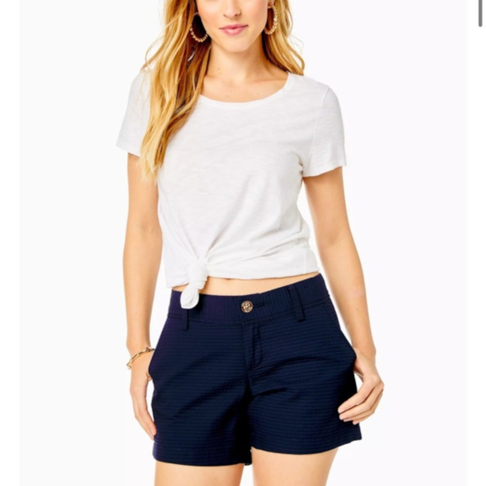 Woman wearing a white t-shirt and Lilly Pulitzer navy shorts on a white background