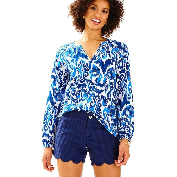 Woman wearing a blue and white patterned blouse with Lilly Pulitzer navy shorts on a white background