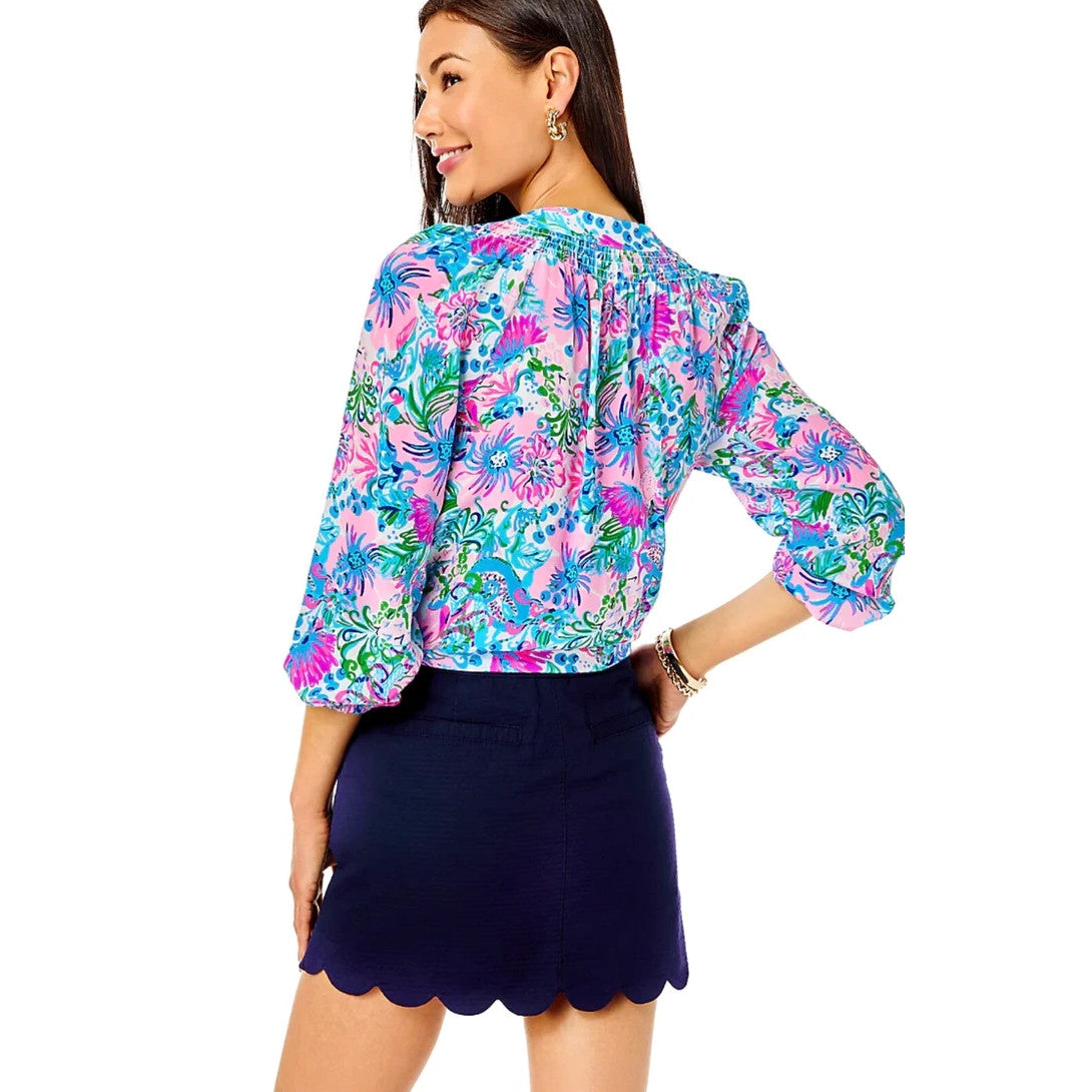 Woman wearing a colorful floral blouse and Lilly Pulitzer navy skirt on a white background